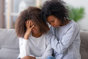 Image of a mother and daughter looking sad together on a couch. This image represents the impacts of racial injustice in Baltimore, MD on Black individuals. Working with an anxiety therapist in Baltimore, MD can help. | 21210 | 21212