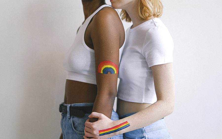 LGBTQ interracial couple hugging, representing how understanding the most common reasons coming out causes anxiety in LGBTQ people can be the first step to find support.