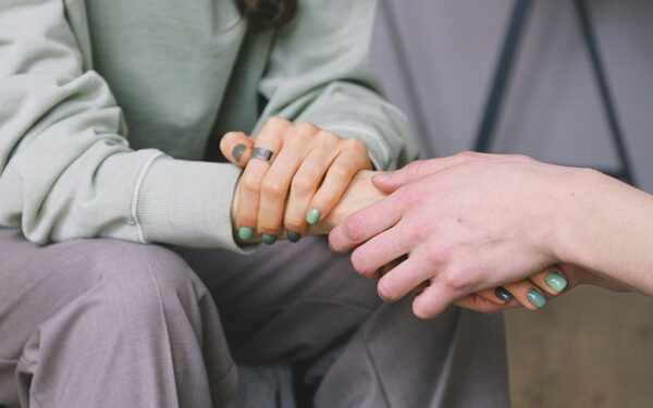 Someone holding the hands and confronting a person who's dealing with trauma, representing how EMDR therapy can help cope with trauma.