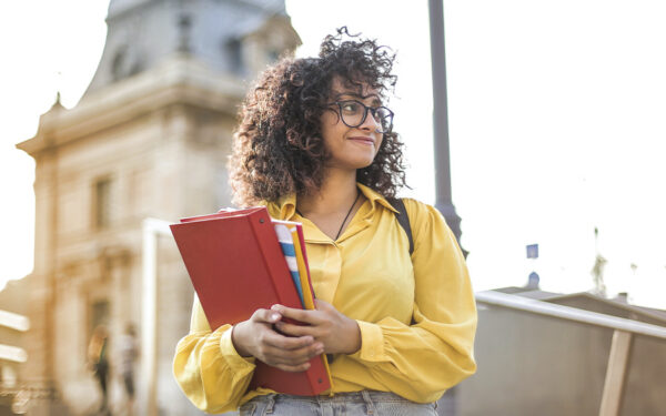 Student holding her school materials and arriving to campus, representing how you can learn what the signs of depression in college students and prepare for a successful and positive experience.