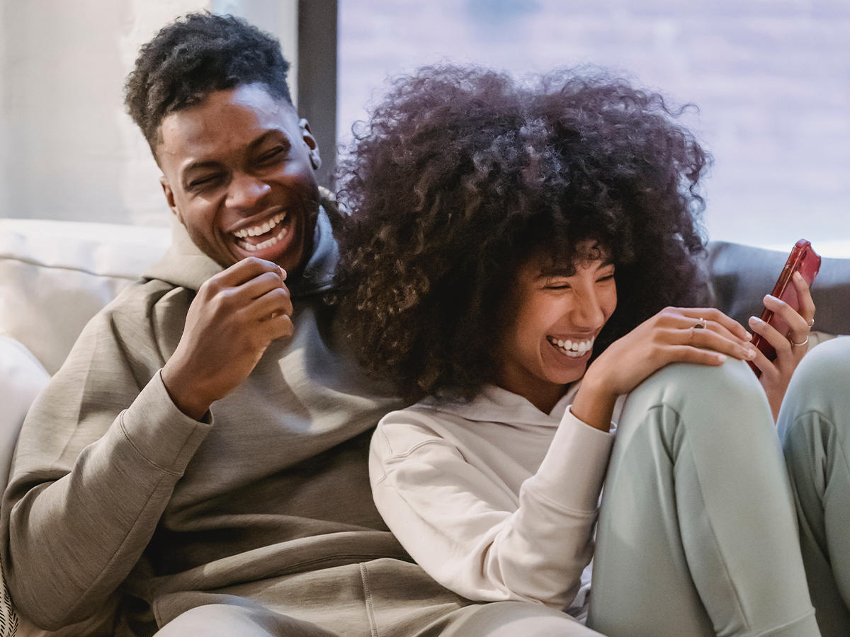 Photo of a BIPOC couple laughing together. This represents how you can take the steps to deal with anxiety in a relationship and feel happier.