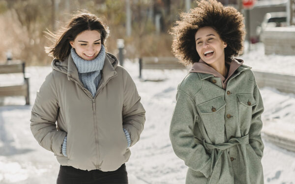 Two women walking outside on a snowy da, representing the steps you can take to reduce the daylight saving time impact on mental health.