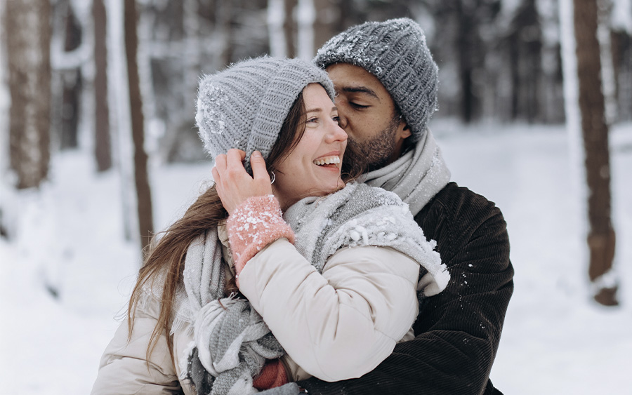 Couple holding each other on a fun snowy day outdoor, representing how you can plan romantic and fun holiday date ideas in Baltimore, MD.