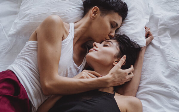 Couple holding each other in bed in a loving moment, representing how couples therapy can help you work through the most common relationship issues together.