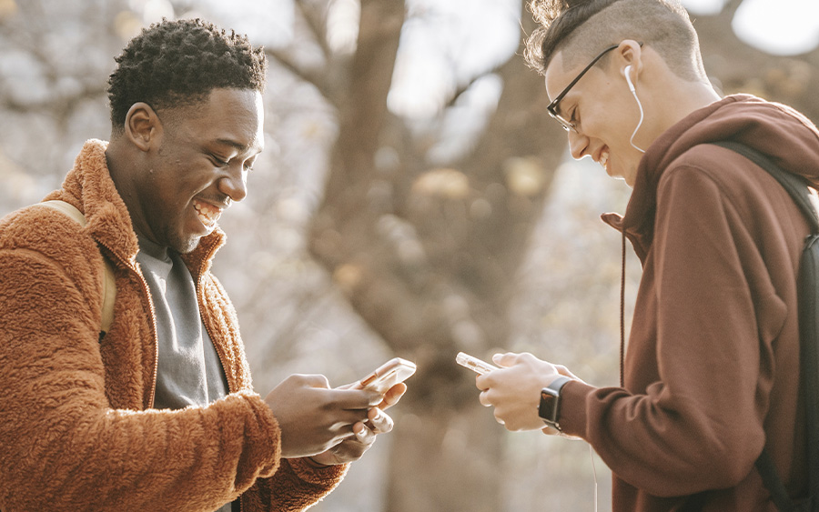 Two young men exchanging phone numbers after connecting on a dating app, representing the importance of keeping up with tips for LGBTQ+ folks using dating and hookup apps.