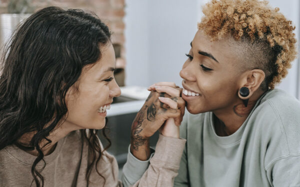 LGBTQ couple looking at each other and holding hands, representing how checking in on your relationship helps you maintain connection and intimacy.