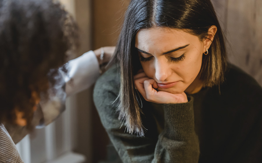 Woman a woman comforting a friend who is suffering from anxiety. This represents how learning about what causes anxiety can help you gain strategies to cope better with it.