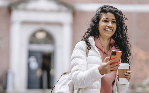 College student happily texting her friends after arriving to campus. This represents how coping with with depression in college has a positive and fulfilling college experience.