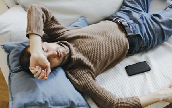 Man lying on the couch looking tired. This represents how depression can make you feel tired, affecting your energy and mood.