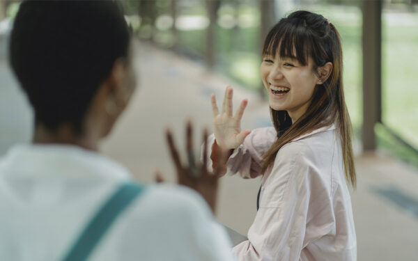 Two young women greeting each other and smiling. This represents how overcoming your social anxiety and perfectionism can help you build stronger and happier connections.