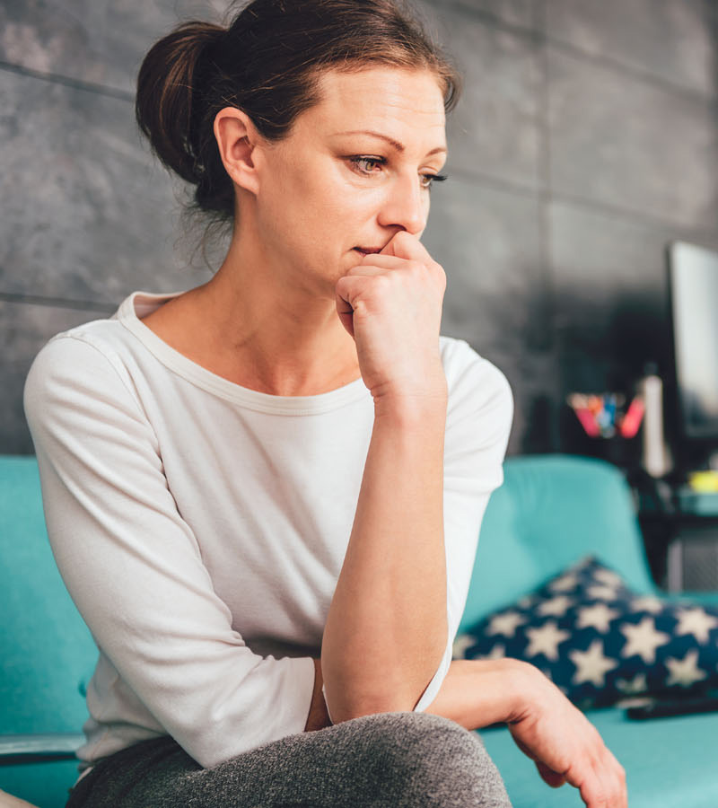 Woman sitting on the couch with her head on her hand looking sad, distraught, depressed and anxious about her life | Therapy for Women | Women's therapy in Baltimore | Help for women's issues | New Connections Counseling Center | Baltimore, MD 21210" width="300" height="200