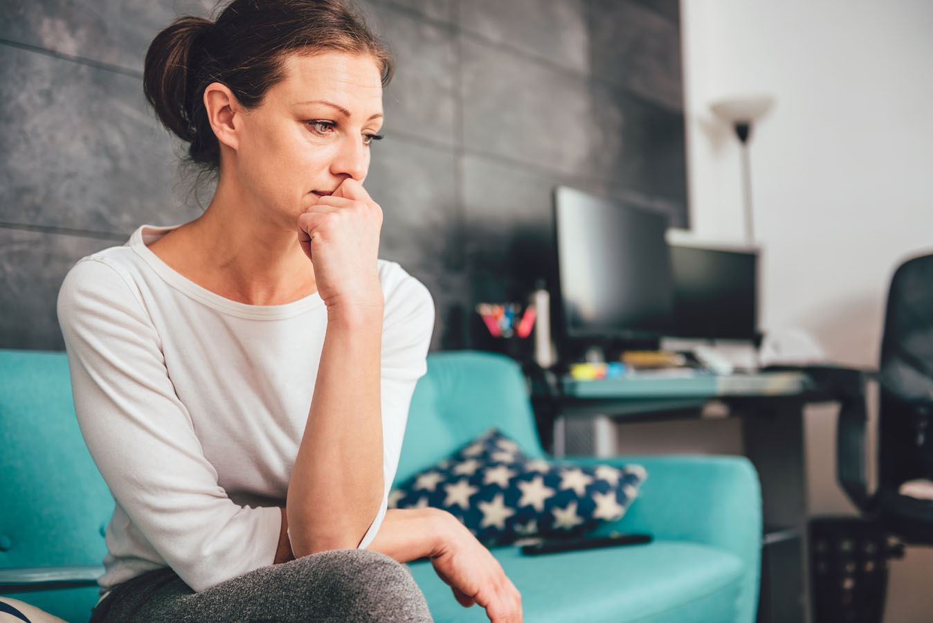 Woman sitting on the couch with her head on her hand looking sad, distraught, depressed and anxious about her life | Therapy for Women | Women's therapy in Baltimore | Help for women's issues | New Connections Counseling Center | Baltimore, MD 21210" width="300" height="200