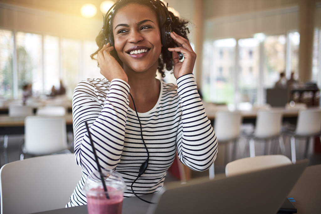 a female college student smiles while listening to music on her headphones after getting help during therapy for college students in Baltimore, MD 21210 at new connections counseling center" width="300" height="200"