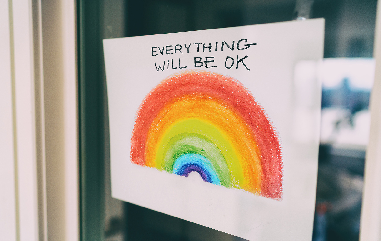 Image of a white sign on a window with a rainbow and the words "everything will be ok." This image represents the support that LGBTQIA+ folks can receive in LGBTQ therapy in Baltimore, MD. An LGBTQ affirming therapist in Baltimore, MD can help you learn about your identity. | 21210 | 21212" width="377" height="239"