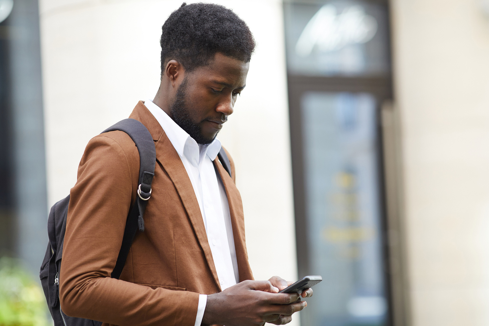 African American man in suit looking at his smart phone in Baltimore | Therapy for Anxiety | Anxiety Treatment | New Connections Counseling Center | men's therapy in Baltimore, MD 21210" width="300" height="200"