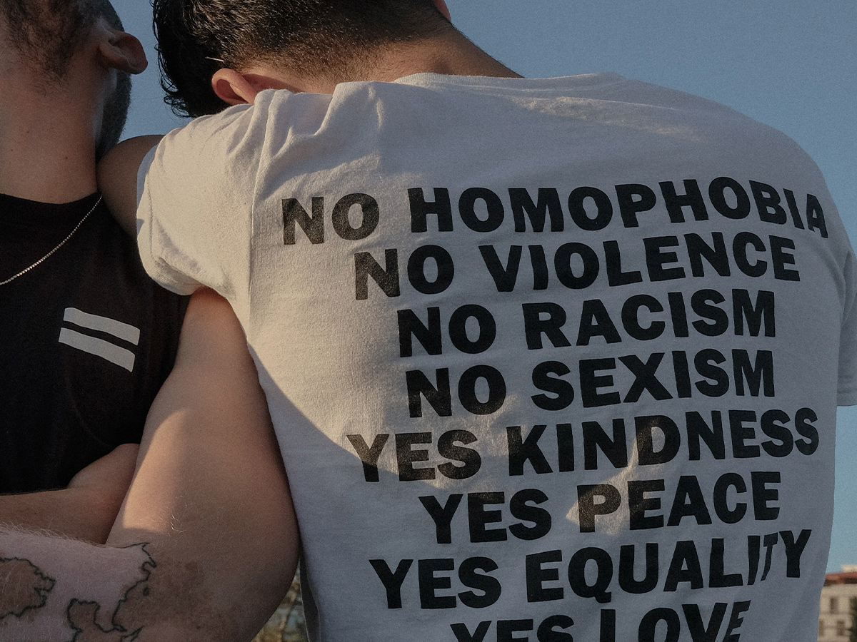 T-shirt back with messages against homophobia and violence and pro equality and love. This represents the New Connections therapists' approach on gender affirmation care." width="300" height="225" 