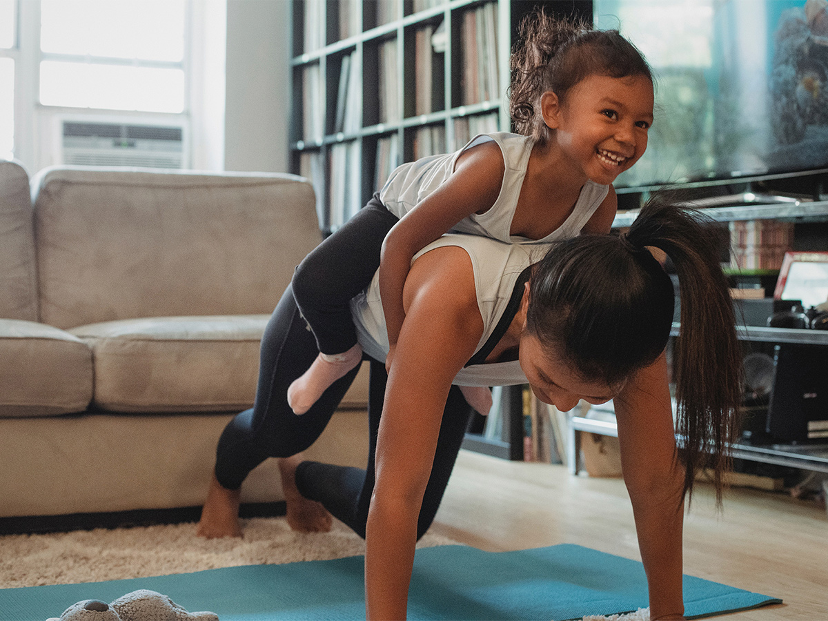 Photo of a mother doing pushups with her child on her back laughing. This represents how finding support from a group of other that are living similar experiences can help you learn new skills and feel relief.