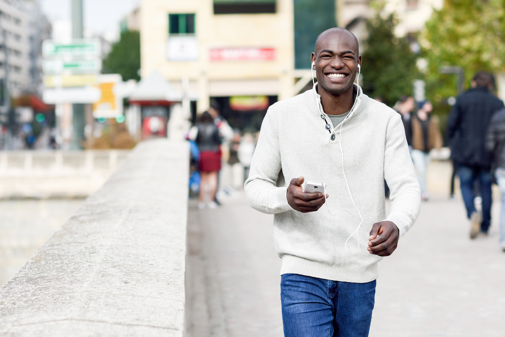 Happy african american man walking on the streets of Baltimore, MD after feeling confident with life changes from going to counseling for life transitions in Baltimore, MD 21210 at New Connections Counseling Center" width="300" height="200"
