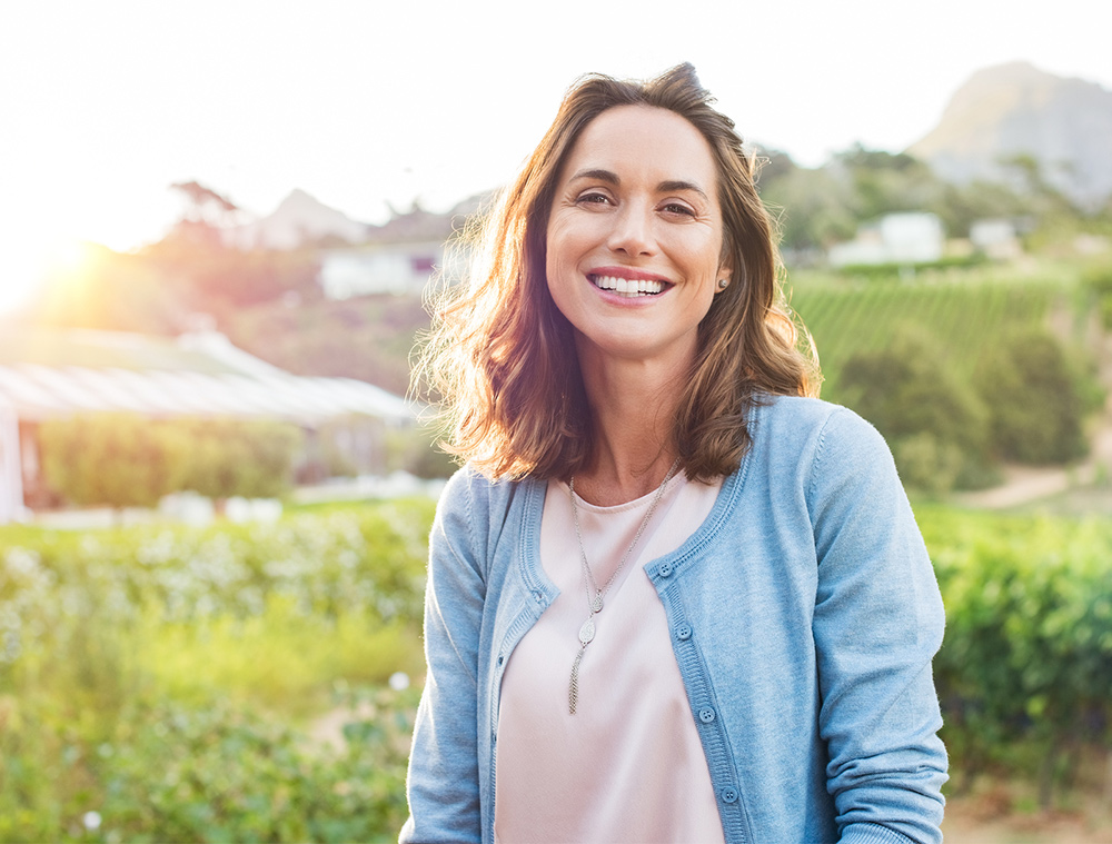 cheerful woman outdoors smiling after finding freedom for problematic drinking. Begin alcohol abuse treatment and therapy in Baltimore, MD 21210 at New Connections Counseling Center