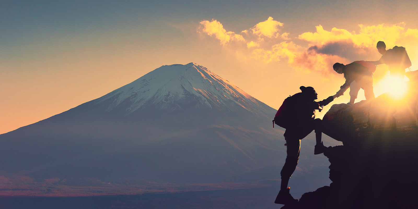 Image of three people hiking a mountain with a sunny and mountainous background. This image illustrates what trauma therapy and PTSD treatment in Baltimore, MD may be like. Processing trauma and PTSD is hard, but worth it. | 21210 | 21212