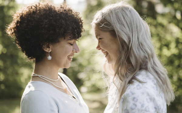 LGBTQ couple happily looking at each other. This represents how working with an affirming therapist can help you overcome your coming out anxiety and feel safe and confident in your relationship.