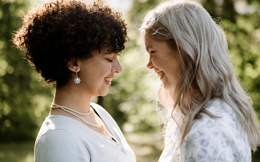 Photo of an LGBTQ couple happily looking at each other. This represents how working with an affirming therapist can help you overcome your coming out anxiety and feel safe and confident in your relationship.