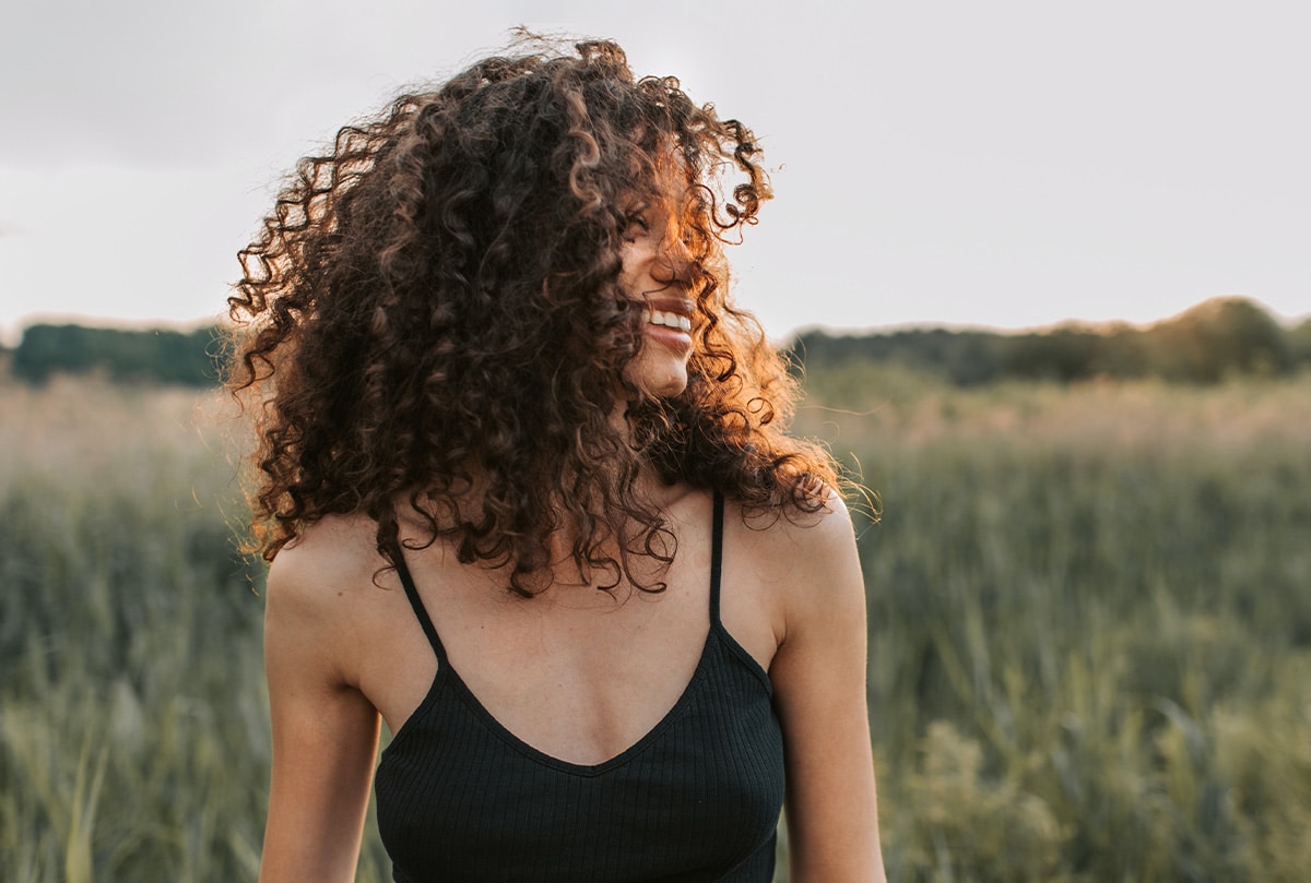 A young black woman smiles in the sunlight. This image represents how New Connections Counseling Center in Baltimore, MD can you help you improve your life and relationships with counseling and therapy services.