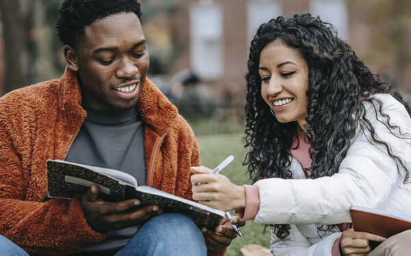 Two students studying together on campus and having a good time, representing how every college student can have a successful experience when they step out of their comfort zone to meet new people, make friends, and even ask for help.