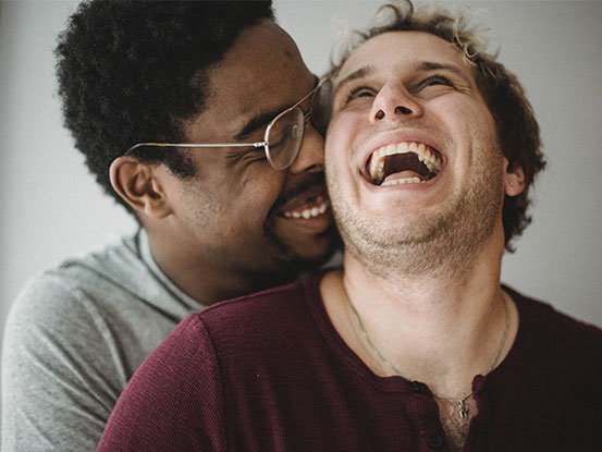 Photo of a gay couple laughing together in a loving moment. This represents how LGBTQ counseling can help you connect with your partner and yourself.