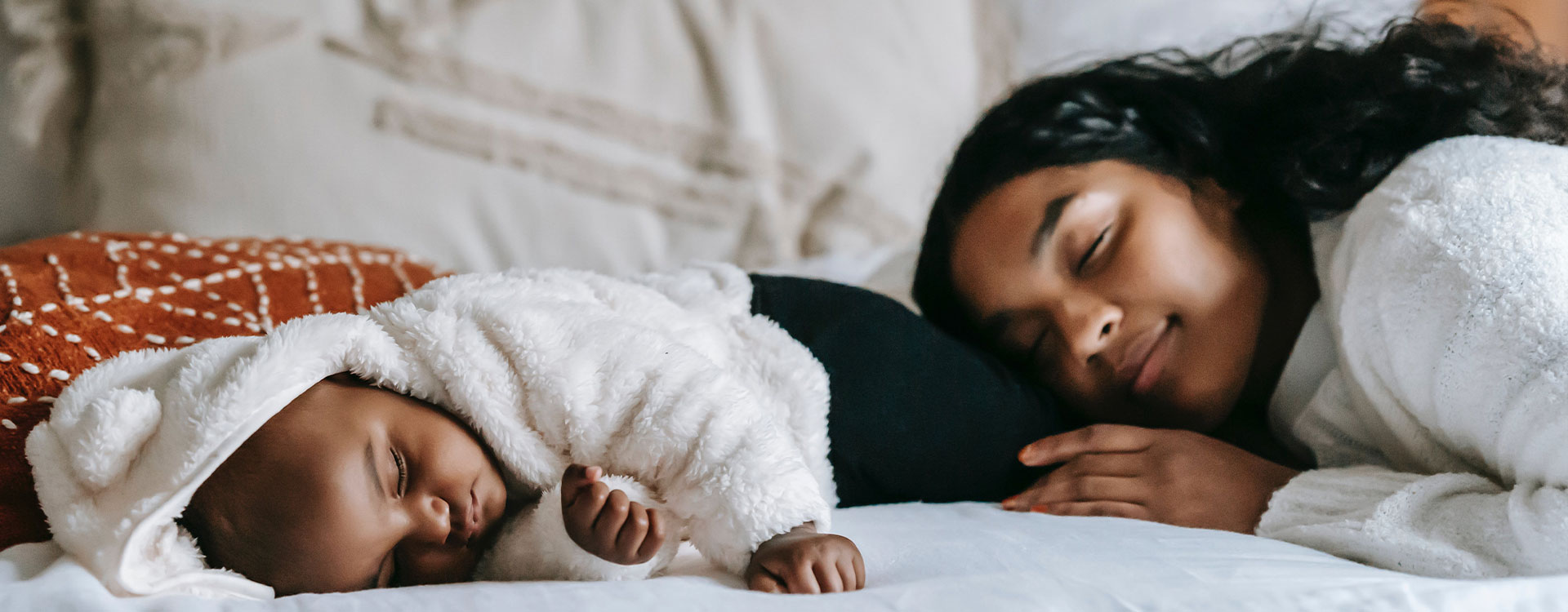 Photo of a mother sleeping beside her baby.  This represents how mothers can feel overwhelmed by all the responsibilities they have to handle alone. A group can help you find the support you need.