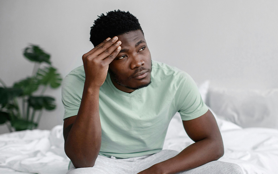 Photo of a black man with his hand on his head and a worried look. This represents how it's crucial to promote awareness about men’s mental health facts and debunk myths.