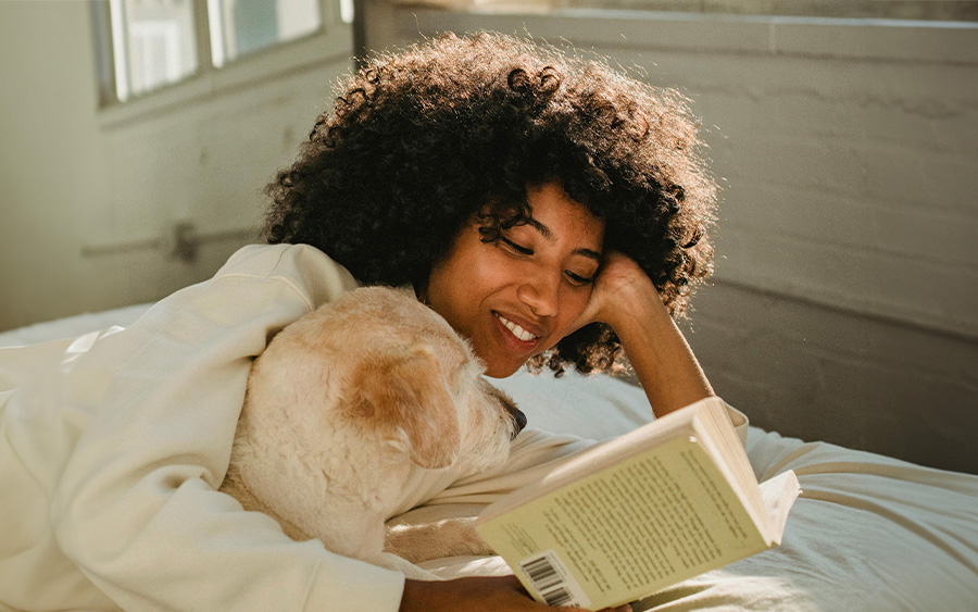 Photo of a woman reading a book with her dog. This represents how work-life balance tips can help you prioritize what really matters to you.