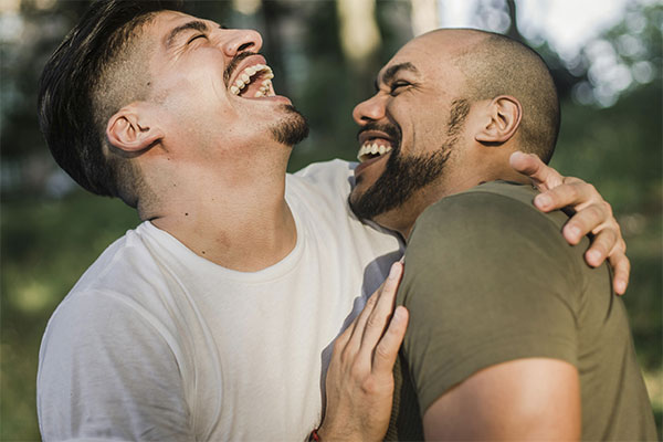 Close up of two men laughing and being affectionate, representing how you can reconnect with your loved one through couples counseling in Baltimore, MD.