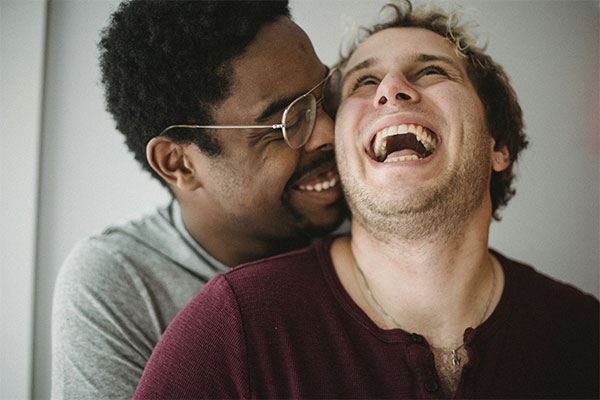 Gay couple laughing together in a loving moment, representing how LGBTQ counseling in Baltimore can help you connect with your partner and yourself.