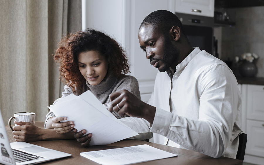 BIPOC couple looking at paperwork, trying to understand if their insurance covers couples counseling and what are the benefits of opting for private pay.