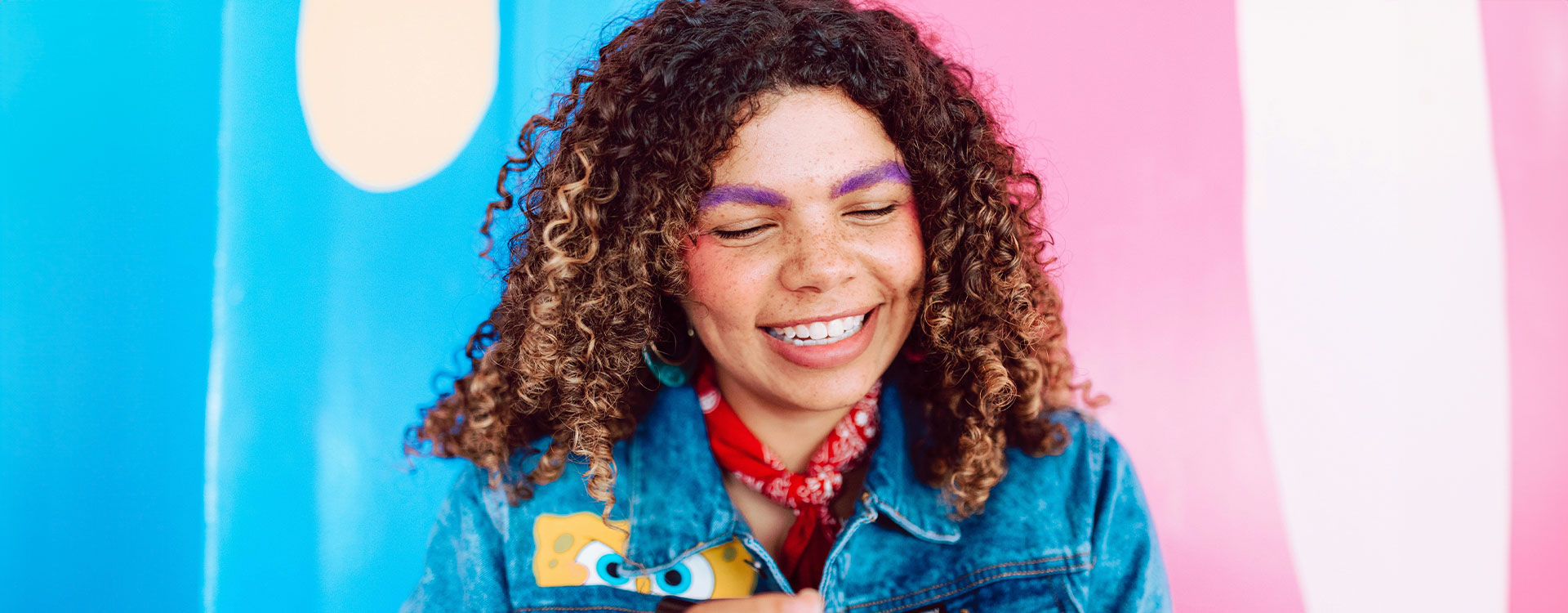 Gender-nonconforming person smiling with the transgender pride flag colours on the background, represents how you can request an evaluation and letter of support for medical care or legal documentation.