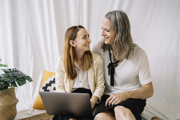 Nonbinary couple smiling at each other, searching on their laptot for gender affirmation letter and evaluation services in Baltimore, MD.