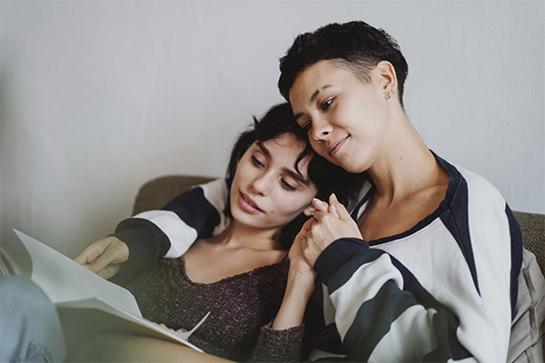 LGBTQ couple reading a book together and holding hands, represents how you can reconnect and rebuild your relationship through couples therapy in Baltimore, MD.